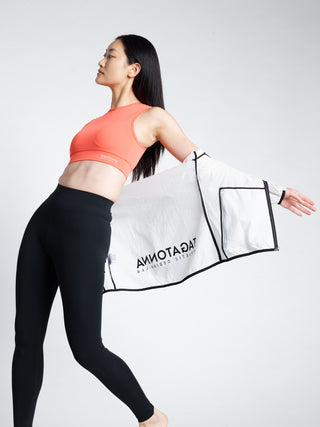 Woman wearing a TAGATONNA white transparent hooded jacket with Coral sports bra and Black leggings