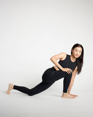 Woman in TAGATONNA black athletic wear stretching