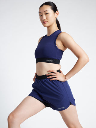 Woman stretching in a blue athletic outfit with a minimalistic TAGATONNA Athletic Design Lab brand