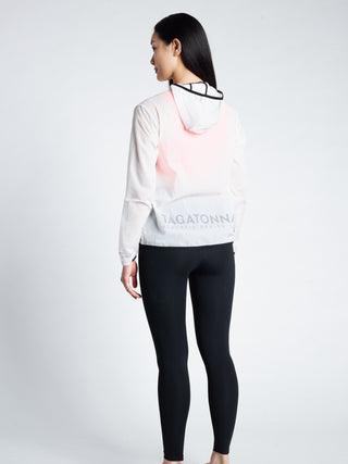 Woman wearing a white transparent  jacket with TAGATONNA ATHLETIC DESIGN LAB logo on lower back   and black leggings 