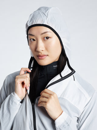 Woman wearing a white TAGATONNA Athletic Design Lab  hooded jacket with a black interior lining 