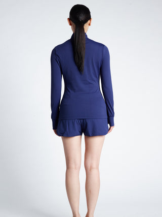 Woman wearing a blue long-sleeve minimalistic TAGATONNA  Mid Layer  with logo and shorts 