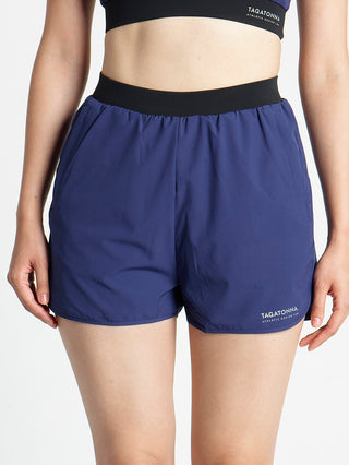 Woman wearing navy blue athletic 2 in 1 shorts with minimalistic TAGATONNA ATHLETIC DESIGN LAB logo
