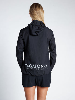 Woman wearing  black jacket  and black shorts with minimalistic TAGATONNA Athletic Design Lab logo on the lower back 
